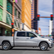 A photo of a silver Ram 1500 pickup truck driving through a city.